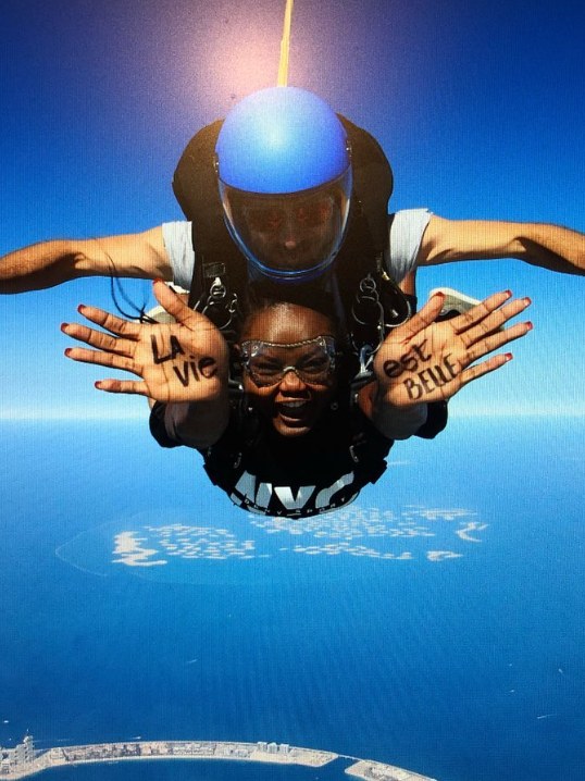 Ife skydiving with La vie est belle written on her hands
